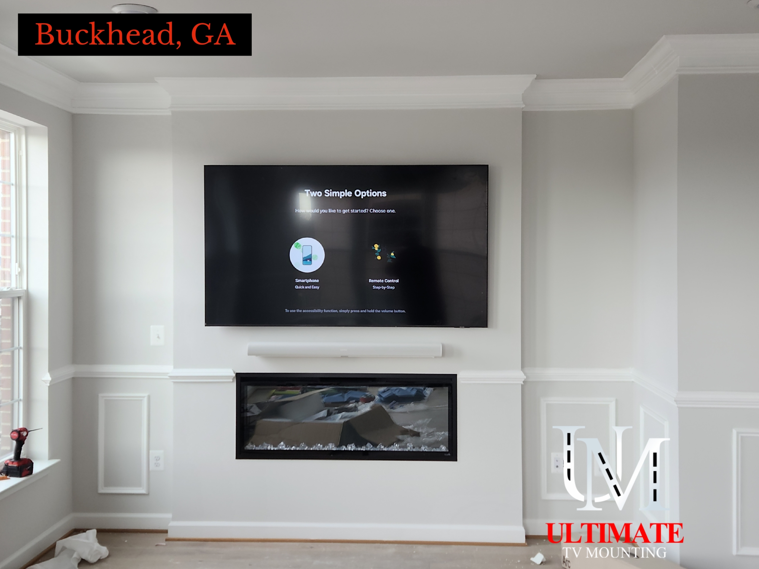 TV mounted above electric fireplace in custom white trimmed bump-out wall in Buckhead, Georgia.