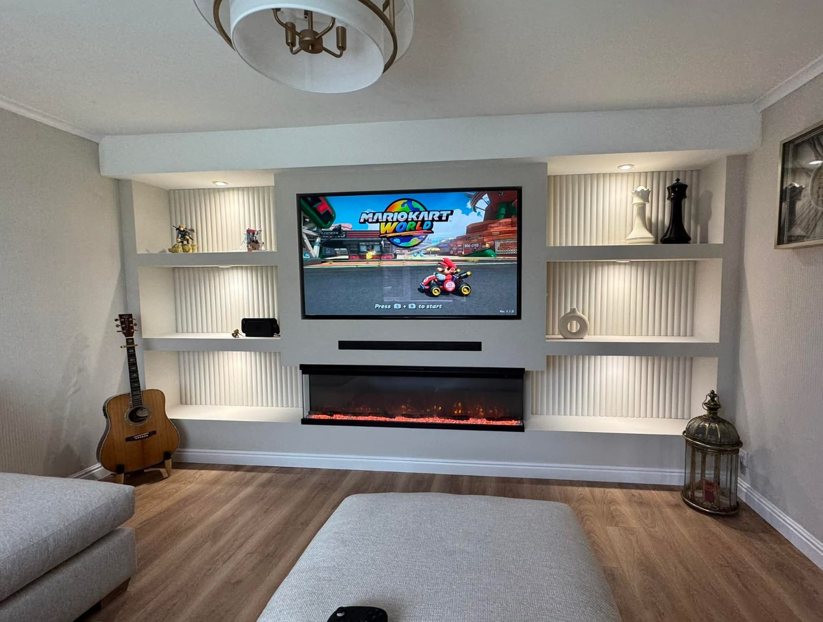 Built-in media wall with LED-lit shelves, floating electric fireplace, wall-mounted TV, and concealed wiring.